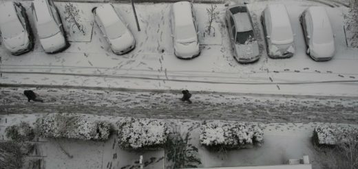A Man Walks Down A Snowy City Road Aerial View Stock Footage